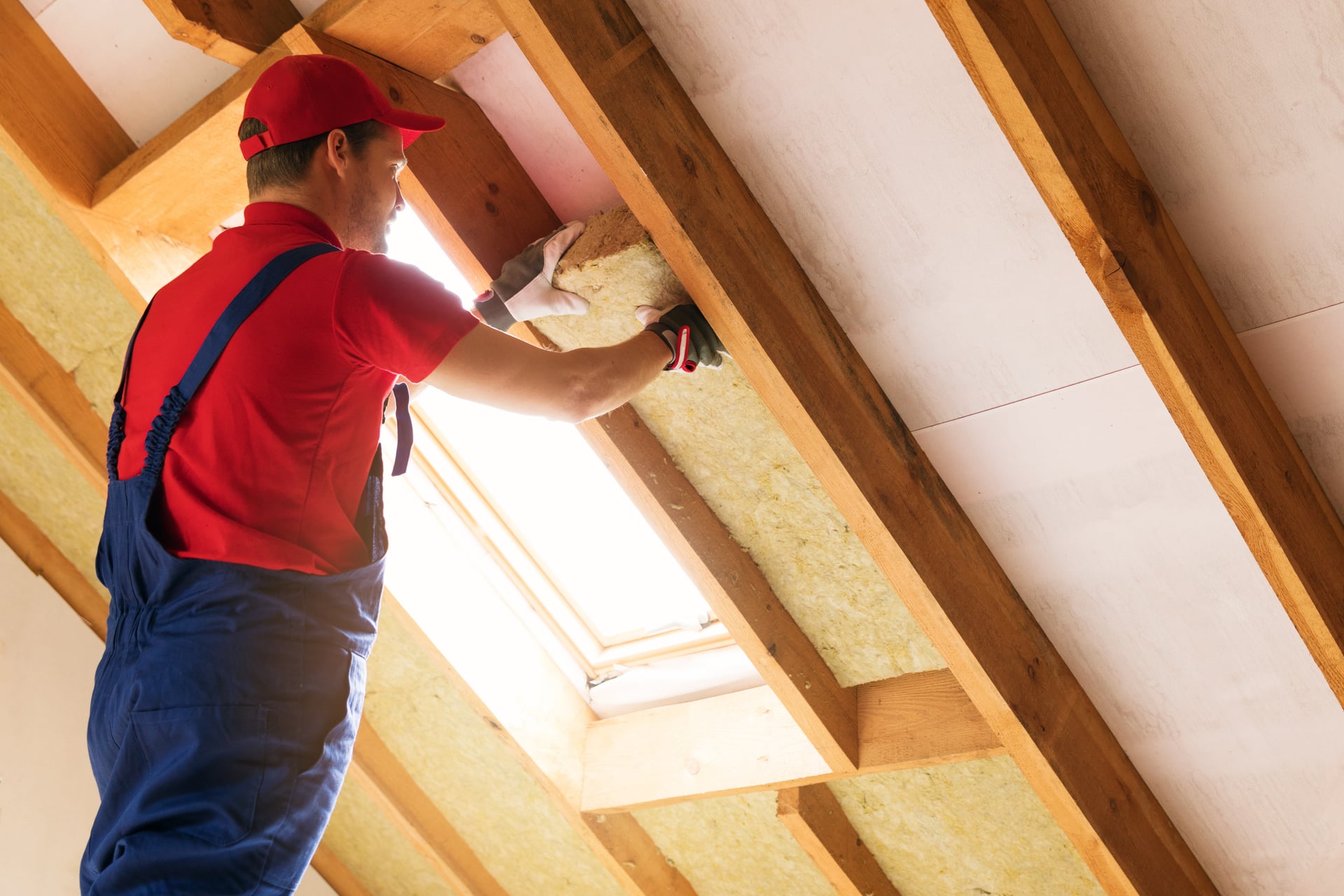 Worker installing batt insulation in attic