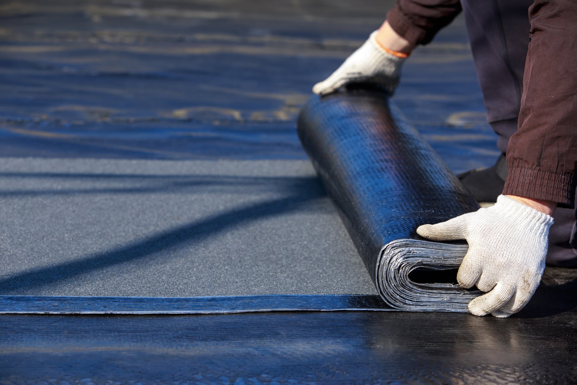 Worker rolling flat roof membrane