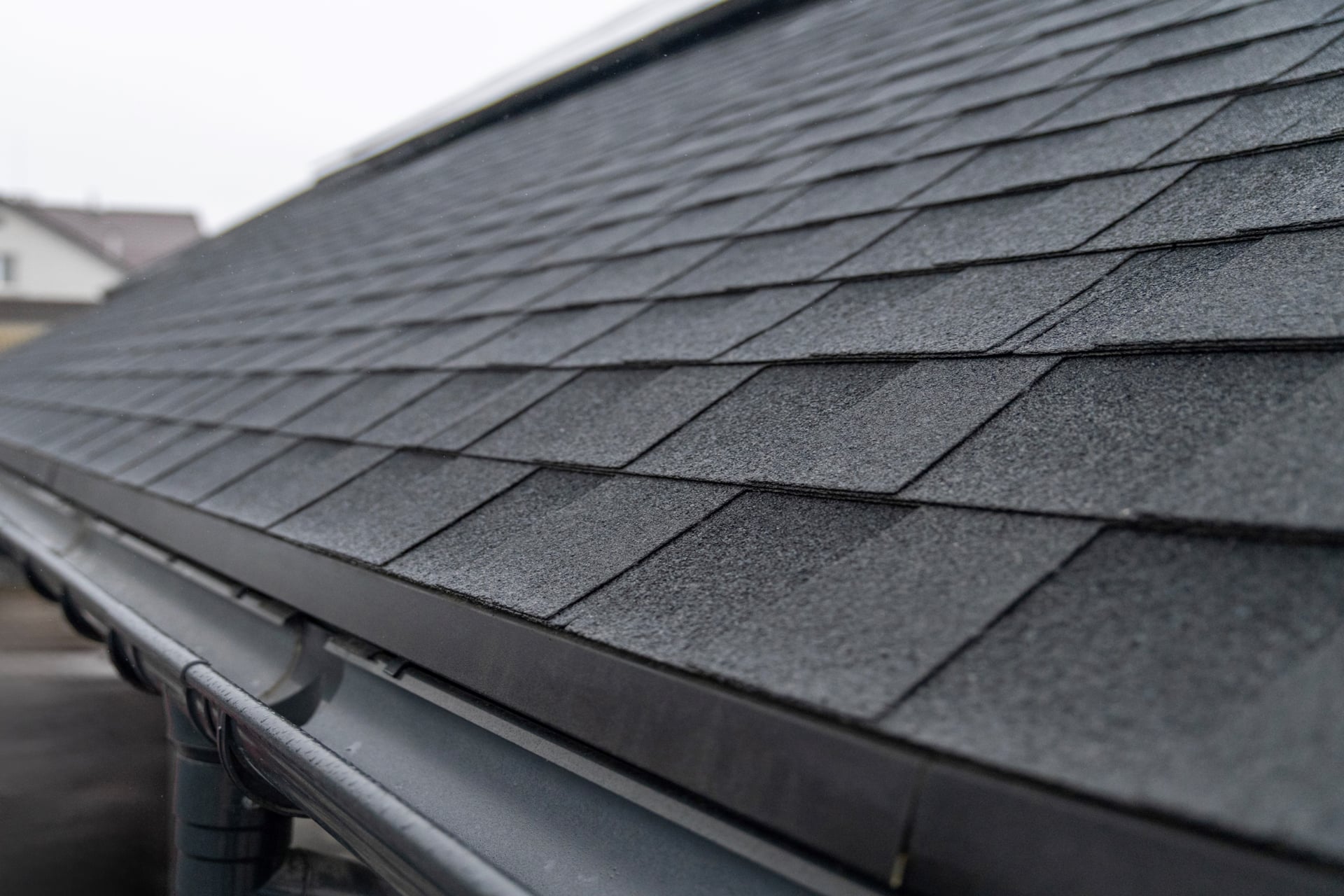 Dark asphalt shingles close-up with gutter