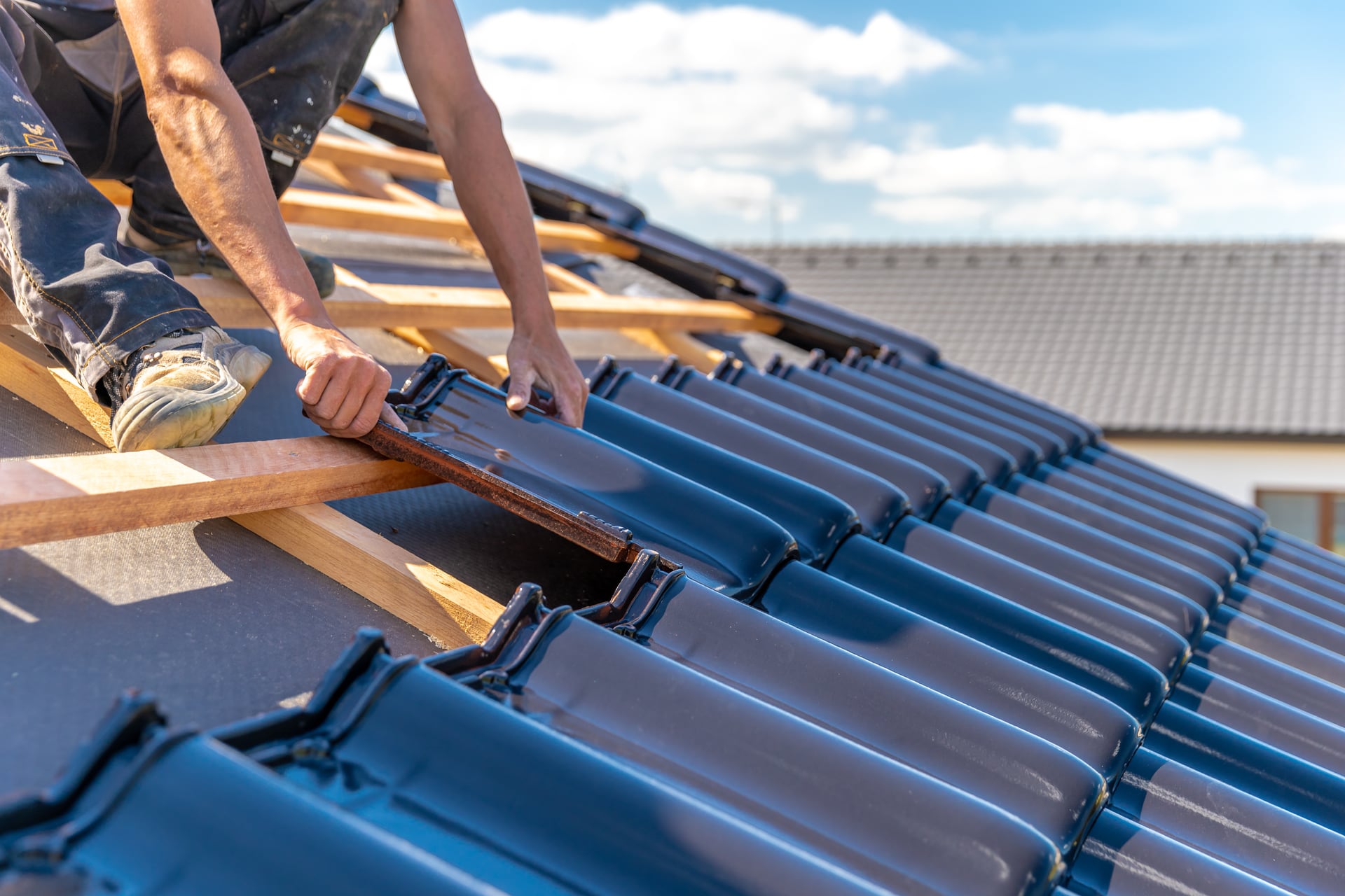Worker installing blue ceramic roof tiles